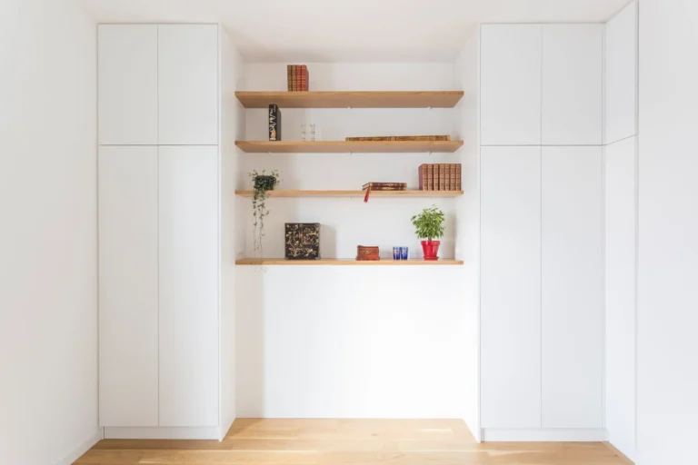 Vue d’ensemble d’un dressing sur mesure avec façades blanches sans poignées et étagères en chêne massif