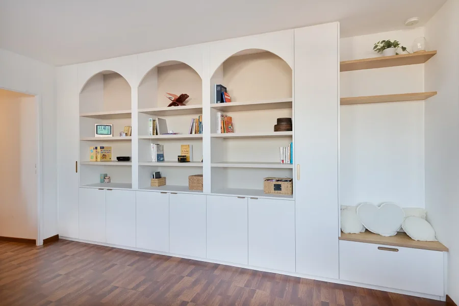 Vue d’ensemble de la bibliothèque arche toute hauteur avec rangements fermés et étagères ouvertes
