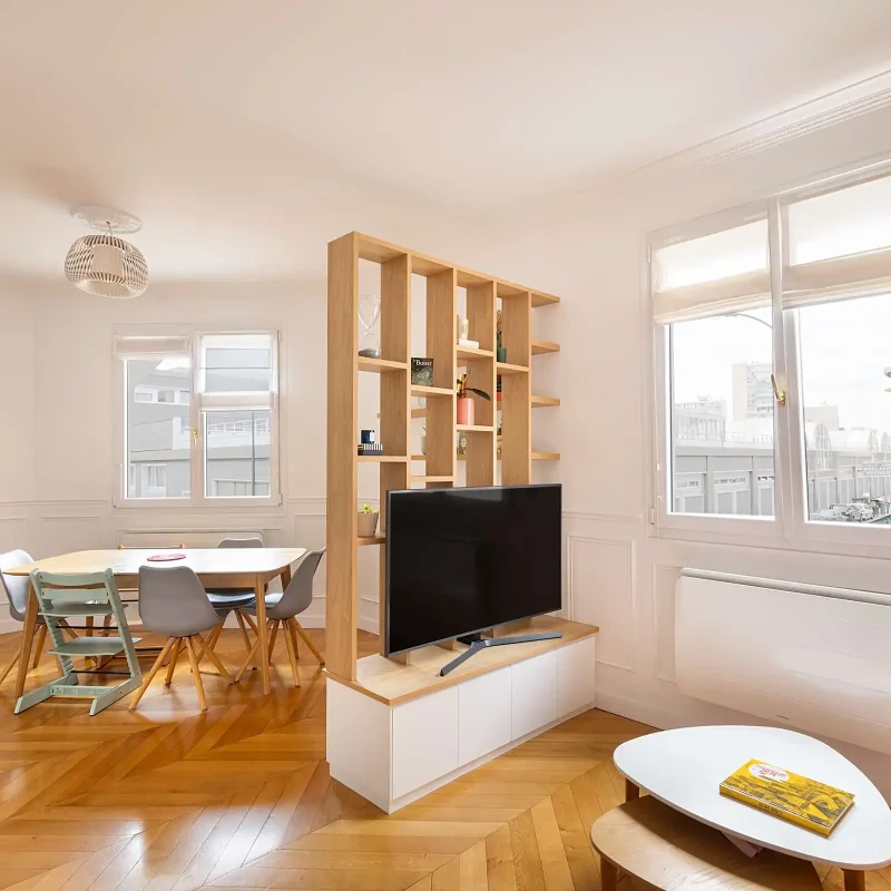 Meuble TV séparation pièce sur mesure en bois clair structurant un salon et une salle à manger dans un appartement lumineux
