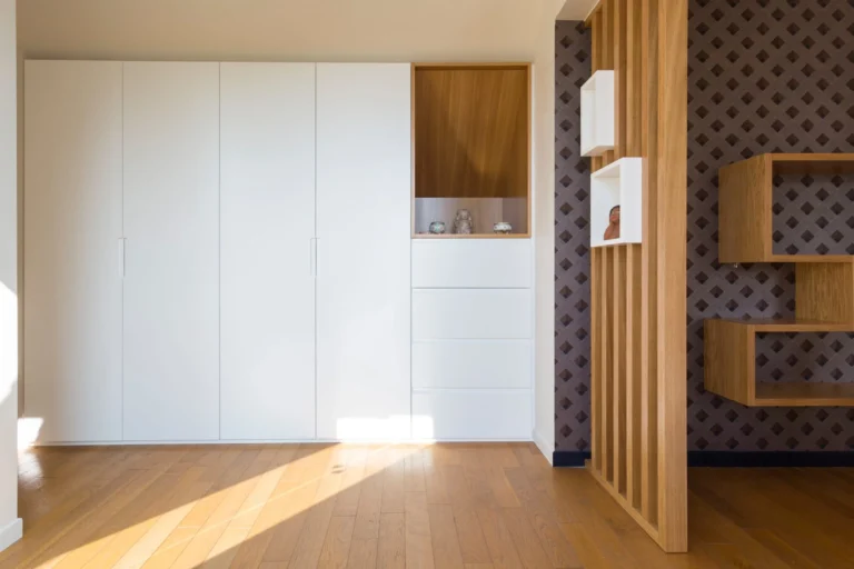vue d’ensemble du dressing sous pente en blanc mat avec niche bois naturel dans chambre mansardée